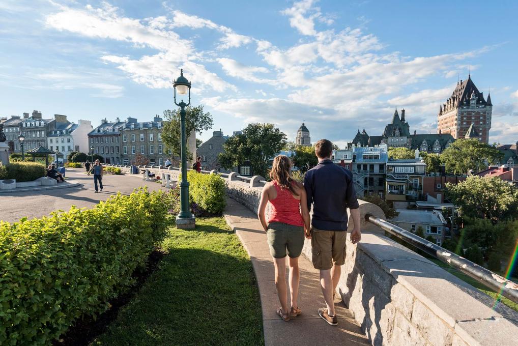 Un couple marche sur la terrasse Pierre-Dugua-De Mons près de l'avenue Saint-Denis, en regardant le Château Frontenac.