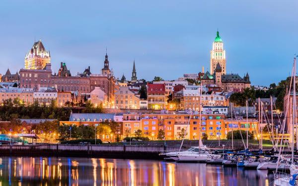 From the Louise Basin, view of the illuminated Old Port, the sailboats, the Château Frontenac and the Price building, in the evening.