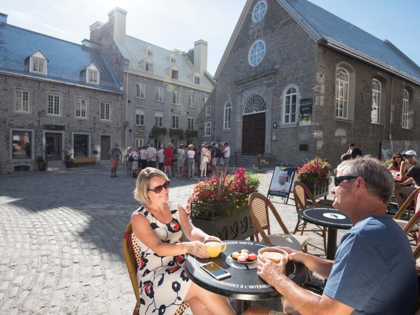 Un couple boit un café à côté de l'église Notre-Dame-des-Victoires, sur la terrasse de la Maison Smith à la place Royale.